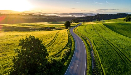 Naklejka premium Aerial View of a Winding Country Road at Sunrise.