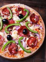 Pizza with chorizo ​​sausage, mozzarella cheese, green pepper and black olives. Rustic wooden background. Soft focus.	