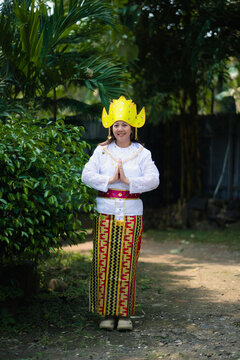 Woman in traditional Lampung costume with white kebaya and yellow siger crown standing outdoors. Useful for cultural, education, and editorial design.