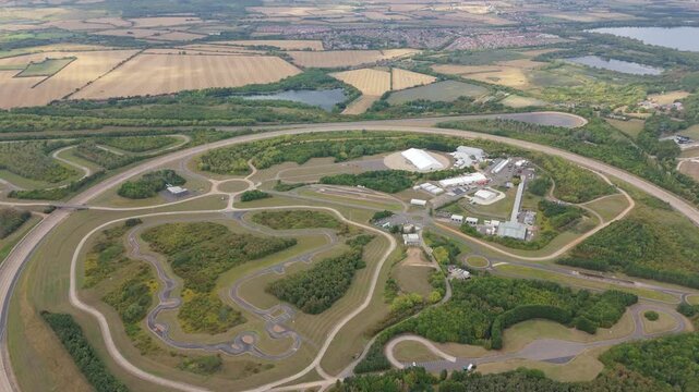 Aerial view of the Millbrook Proving Ground, showcasing its extensive network of test tracks amidst green fields and wooded areas, Bedford, England, United Kingdom.
