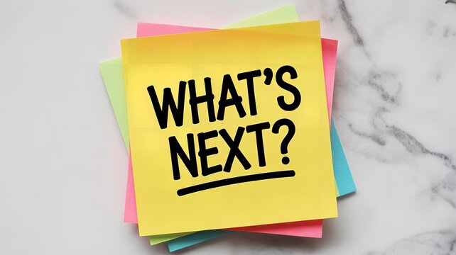 A yellow sticky note on a marble surface asks the question whats next, prompting reflection and anticipation for future endeavors