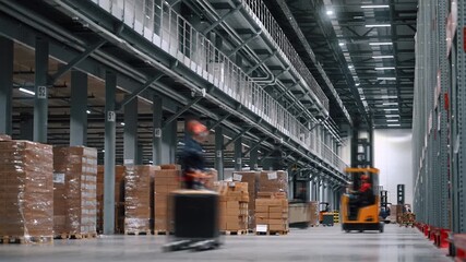 Time lapse footage of a dynamic working day at modern distribution center. Many workers on forklifts together move and transport various goods. Concept of efficient operation of the warehouse - Powered by Adobe