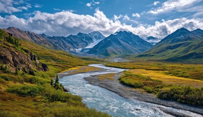 Majestic mountain range and river valley under a cloudy sky.