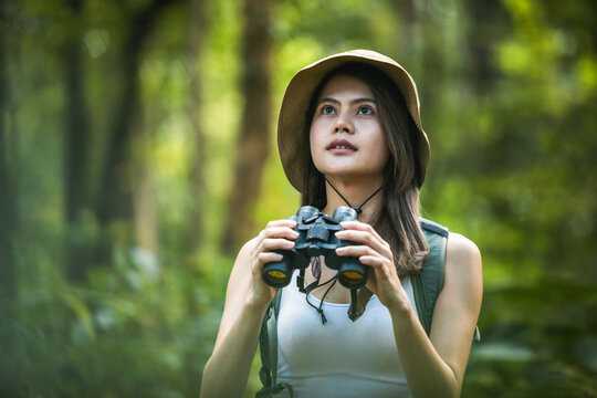 Binoculars, hiking, young woman birdwatching, jungle adventure and nature explore with backpack, close up