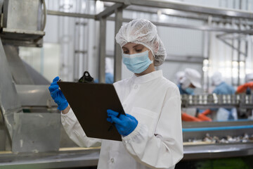 Factory worker working in canned fish factory production line, checking quality of fresh fish while transporting on conveyor belt. Canned fish factory, seafood manufacturing and processing