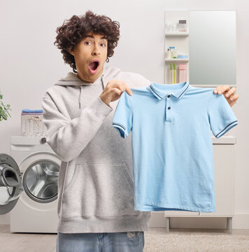 Surprised young man holding a blue t-shirt