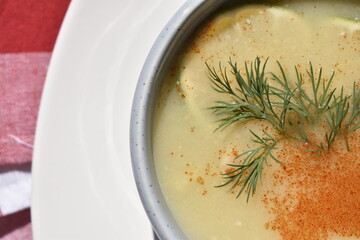 Yellow pea soup garnished with a lemon slice and a sprig of dill, top view