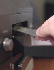 A hand inserting a magnetic tape into a vintage cassette player