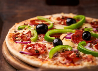 Pizza with chorizo ​​sausage, mozzarella cheese, green pepper and black olives. Rustic wooden background. Soft focus.	