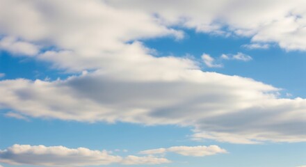 Obraz premium A bright sky with soft white clouds scattered across a blue background. The clouds are fluffy and partially cover the sky, creating a calm and natural atmosphere