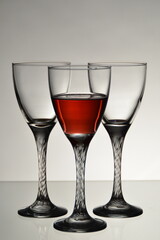 Three wine glasses with one filled with red wine on white background