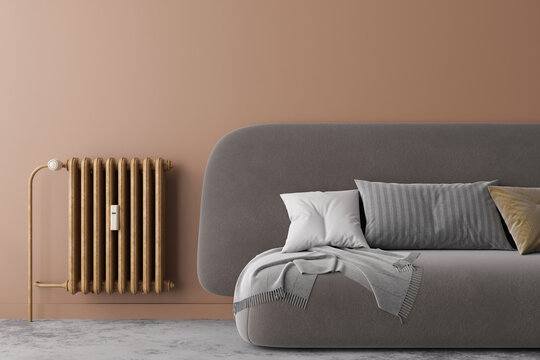 A modern radiator is fitted against a soft-toned wall in a stylish living room. The room features a sleek sofa adorned with decorative cushions, creating a cozy atmosphere