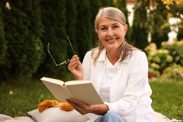 Senior woman reading book on blanket in garden
