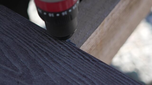 Drill Screwing Wood power tool driving screw into dark composite board