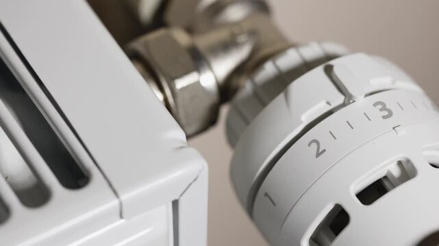 Save energy: close up of Hand Adjusting Heating Thermostat, one hand operates the temperature controller radiator,