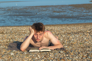 Teenage Boy Reading On A Beach