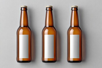 Three amber glass beer bottles, each with a blank rectangular label, sit on a light gray surface, viewed from directly above