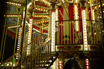 Carousel at night, with vintage style decorations and glowing lights illuminating structure....