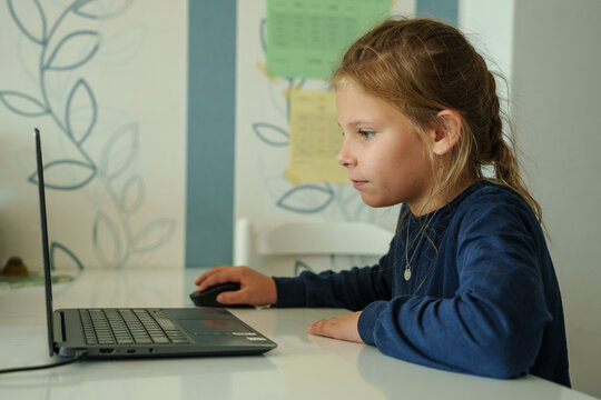 Young schoolgirl stares intently at a computer screen. Illustrating e-learning, distance learning and home schooling.  - Powered by Adobe