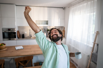 Happy man stretching in kitchen enjoying morning coffee