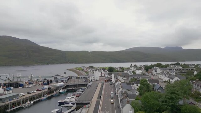 Drone view of Ullapool town and harbour on Loch Broom in the Scottish Highlands under cloudy sky
