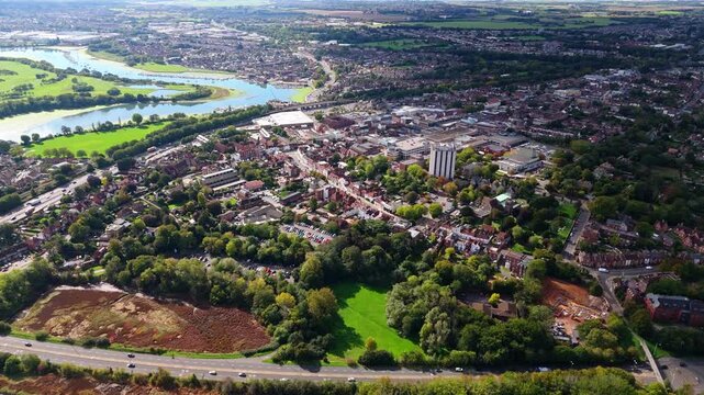 Aerial drone pans right over Fareham town, capturing river, trees, roads, and autumn colours glowing warmly in golden sunset light across the scenic English countryside landscape.
