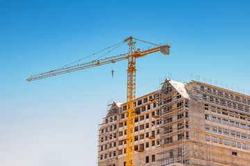 Crane overseeing a new building site, indicating urban growth and real estate development. Modern apartments are under construction