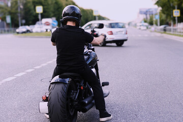 Motorcycle rider waits at intersection on a sunny day in a bustling urban area