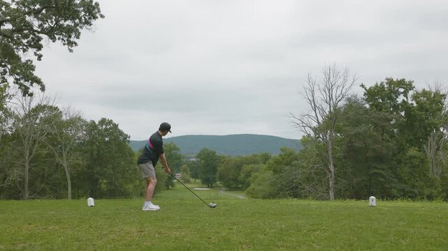 Golfer swings a driver off the tee box on a lush golf course, ideal for sports, recreation, and outdoor activity visuals.