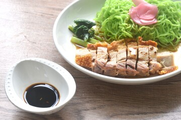 Chinese jade noodles topping roasted crispy pork and cabbage with pnk pickled ginger dipping sweet soy sauce on plate 