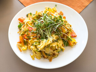Delicious veggie scramble with fresh sprouts on white plate