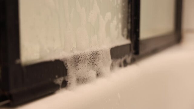 De la mousse qui d&eacute;gouline d'une porte dans une salle de bain.