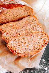 Freshly baked bread displayed on brown paper with slices cut and ready to serve
