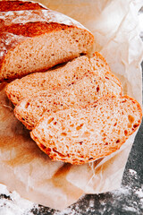 Freshly baked bread with slices on parchment paper in a cozy kitchen setting