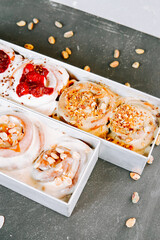 Freshly baked cinnamon rolls with various toppings displayed on a textured gray surface