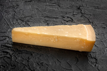Parmesan cheese wedge on a black stone background