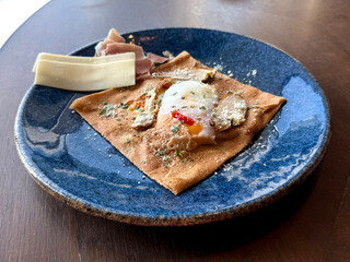 Baked Egg with Vegetables and Herbs in a Crepe Wrap. Outdoor Breakfast Concept. Handmade Phone Photo, Selective Focus, No AI