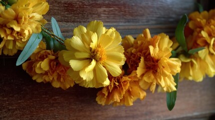 Close-up of a bunch of yellow flowers with green leaves. the flowers are arranged in a cluster and are placed on a wooden surface.