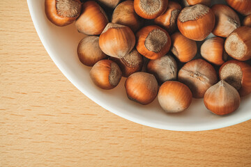 Hazelnuts arranged beautifully in a white bowl on a wooden table
