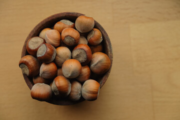 Freshly harvested hazelnuts gathered in a wooden bowl on a rustic table