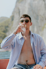 Portrait of a young man drinking champagne in a boat.