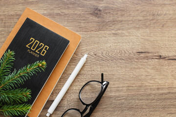 Stylish Desk Setup With 2026 Planner, Notebook, Pencil, Glasses on Wooden Surface