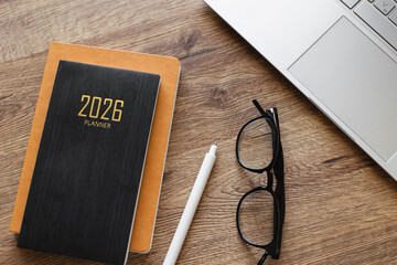 2026 Planner On Desk With White Pen, Glasses and Laptop On Wooden Surface for Office, Productivity, and Organization