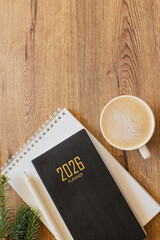 Stylish Desk Setup With 2026 Planner, Notebook, Pencil, Glasses, and Coffee on Wooden Surface