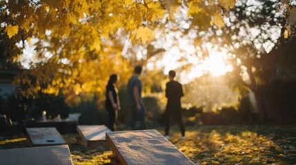 Group of people walking in a park during autumn. the sun is shining through the trees, creating a warm glow that illuminates the scene.