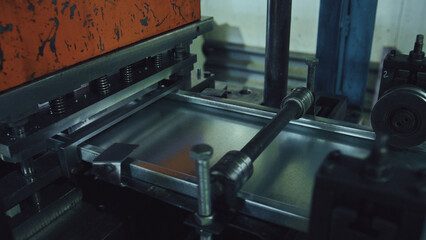 Industrial press machine processing a flat metal sheet, bending and shaping it into new components within a factory production line, demonstrating precision manufacturing and engineering