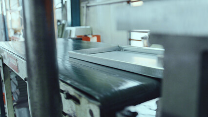 Metal frame moving on a conveyor belt, representing a manufacturing process in an industrial factory setting, showcasing automation and production line efficiency