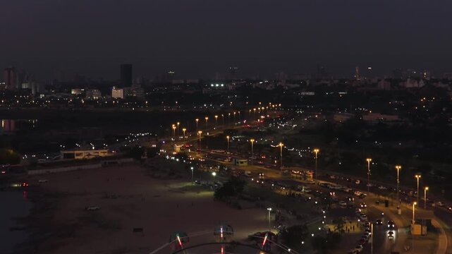 Close up aerial of Ferris wheel at Ecko Park with Costanera Avenue at night, Asuncion