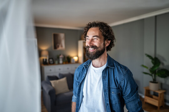 Confident man smiling looking away in living room - Powered by Adobe