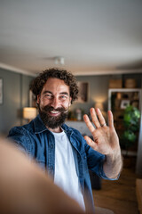 Man waving hand during video call from home